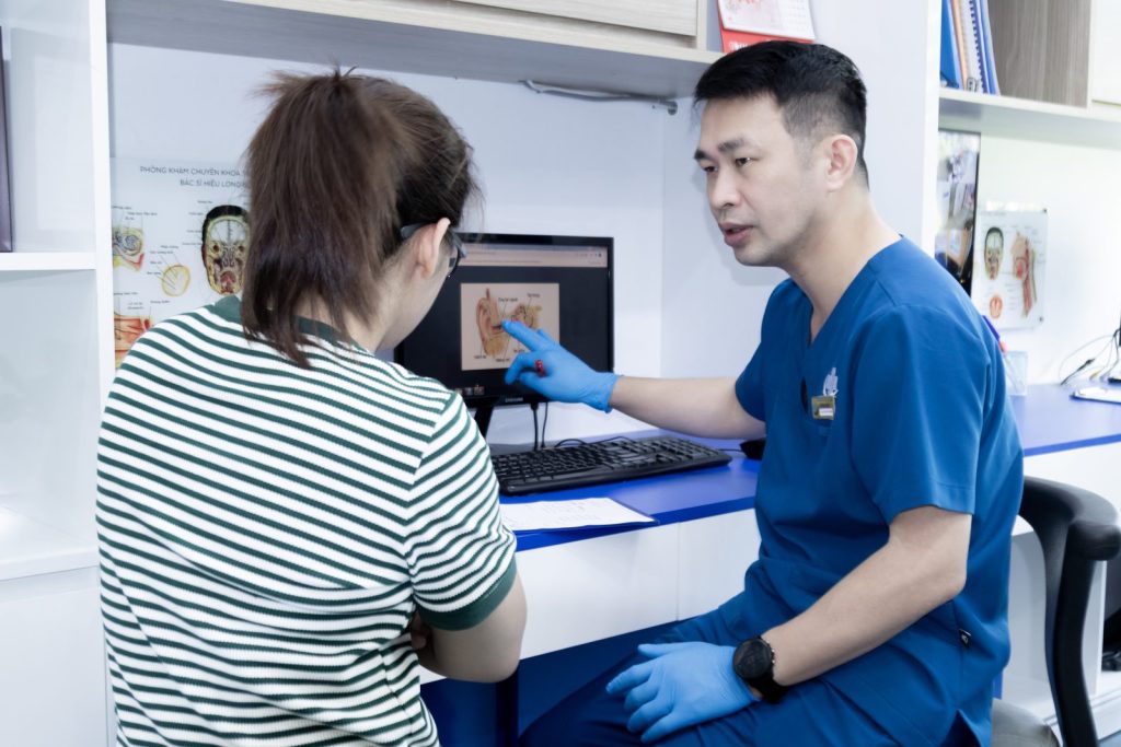 ThS.BS Phùng Tiến Hiệu giải thích cấu trúc tai trên màn hình cho người bệnh nữ tại phòng khám