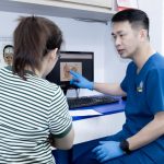 ThS.BS Phùng Tiến Hiệu giải thích cấu trúc tai trên màn hình cho người bệnh nữ tại phòng khám